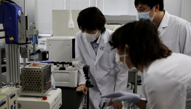 الأستاذ بجامعة أوساكا ميتسوساكي وزملاؤه الباحثون ينظرون إلى طابعة ثلاثية الأبعاد في مختبر بجامعة في سويتا، محافظة أوساكا، اليابان، 5 أكتوبر/ تشرين الأول 2021.
